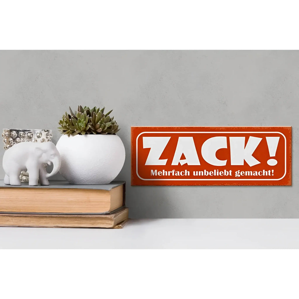 Orange rechteckiges holzschild 27x10cm mit weißem schriftzug zack und kleinem deutschen spruch darunter