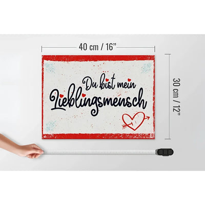 Ein rechteckiges weißes holzschild 30x40cm mit rotem rahmen, schwarzem kursivtext du bist mein lieblingsmensch und rotem herz mit pfeil