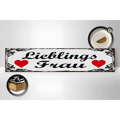 Weißes holzschild mit schwarzem ornamentrahmen und text lieblingsfrau plus roten herzen im vintage metalllook