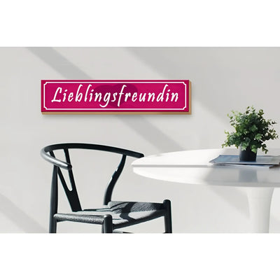 Ein rechteckiges pinkes holzschild mit weißer kursiver schrift lieblingsfreundin und hellem holzrahmen für geschenk und deko