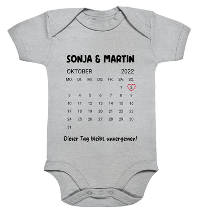 Grauer babystrampler mit schwarzem oktober 2022 kalender und rotem markierungskreis am 2 mit sonja und martin text