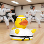 Gelbe quietsche-ente in weißem karate-gi mit schwarzem gürtel und stirnband fürs bad und kampfsportspaß