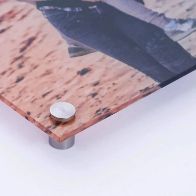 Ein kupferfarbenes acrylglasbild mit sprenkelstruktur auf silbernem metallständer aus der grimassenbande serie