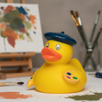 Gelbe gummiente mit marineblauem barett und malerpalette als künstler badeente zum quietschen