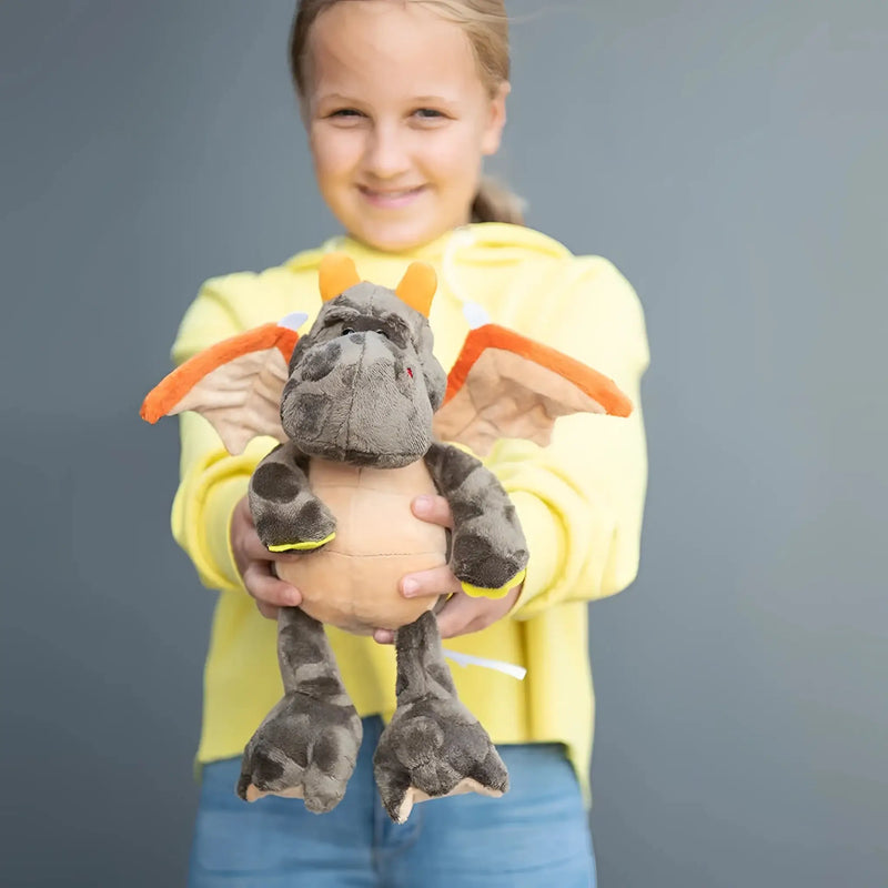 Ein plüschiger grauer mini feet drache edda mit orangen flügeln und gelben akzenten als kuschelheldin ab 10 monate