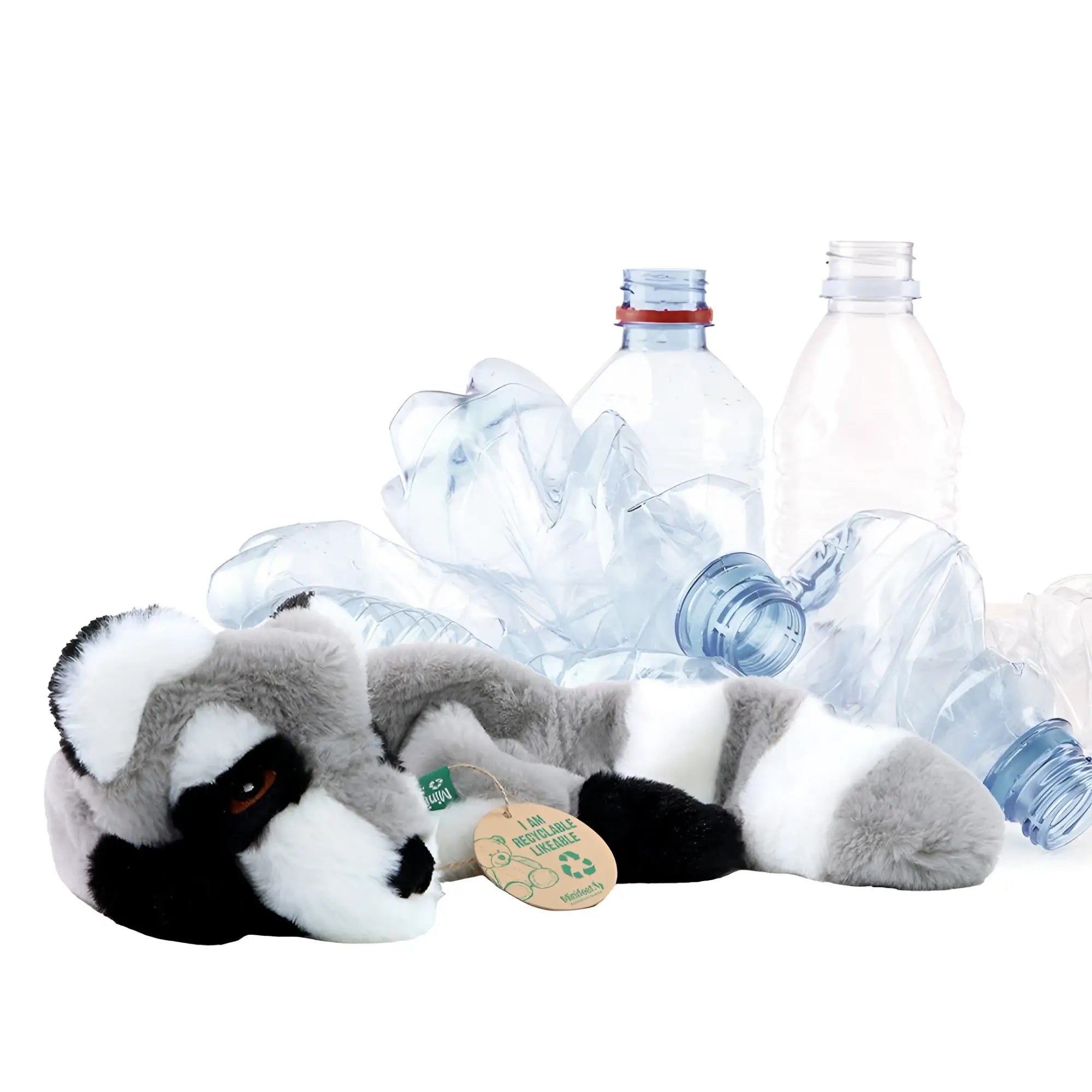 Grau weißes plüsch-waschbär-hundespielzeug von minifeet liegt umgeben von zerknüllten plastikflaschen