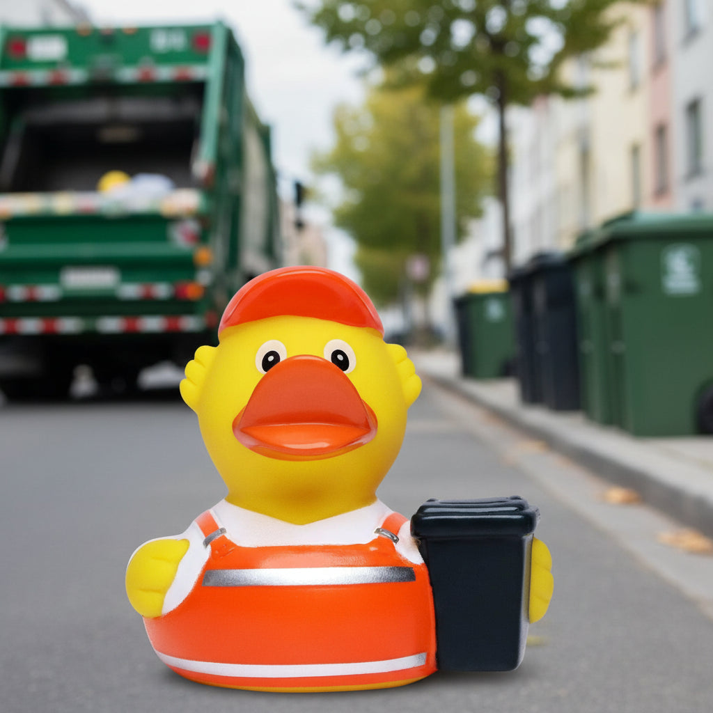Eine gelbe quietsche-ente als müllmann mit oranger baustellenmütze und reflektierender arbeitskleidung mit müllcontainer