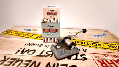 Vintage silberne spieluhr happy birthday mit schwarzem griff und sichtbaren metallzahnrad im happy birthday packaging