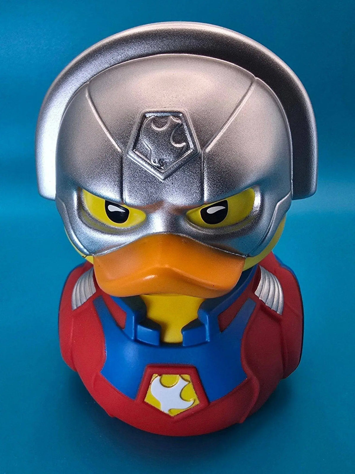 Silberner helm-ente figur im roten und blauen peacemaker-superheldenkostüm mit gelben augen pvc sammlerente
