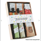 Personalisierbare banderole auf geschenkbox mit grünen und beigen soßenflaschen, roten bonbons und markenverpackungen