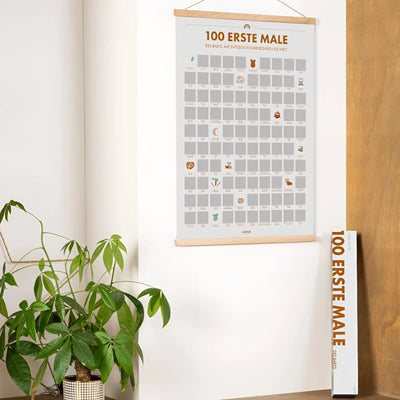Minimalistischer rubbelposter die 100 ersten male deines kindes mit holzrahmen grauem hintergrund und orangen texten