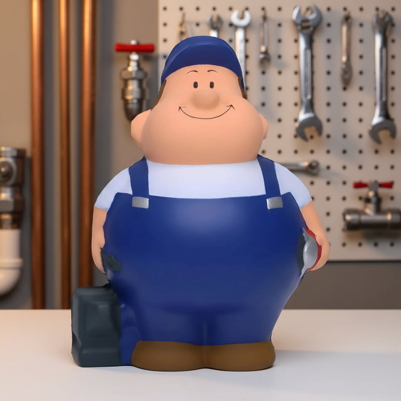 Blaue cartoon-schlosser bert anti-stress-quetsch-figur in kappe und overalls mit braunen schuhen und werkzeugkasten