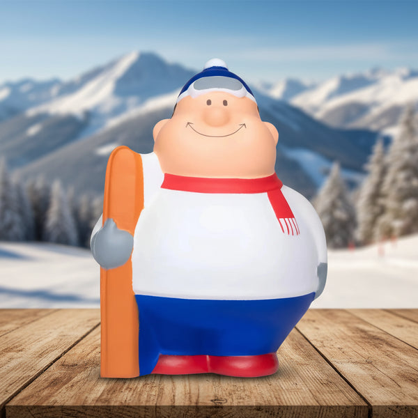 fröhliche cartoon ski bert anti-stress-figur mit weiß-blauem Outfit, rotem schal und orangen skis