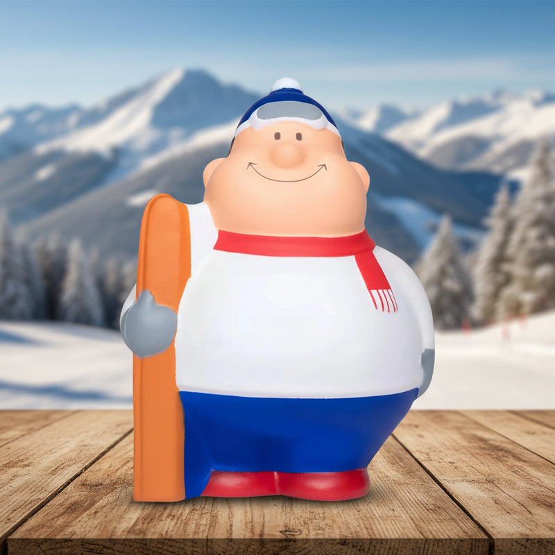 fröhliche cartoon ski bert anti-stress-figur mit weiß-blauem Outfit, rotem schal und orangen skis