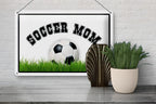 Weißes rechteckiges blechschild mit schwarzem soccer mom text und fußballmotiv auf grünem gras 20x30cm