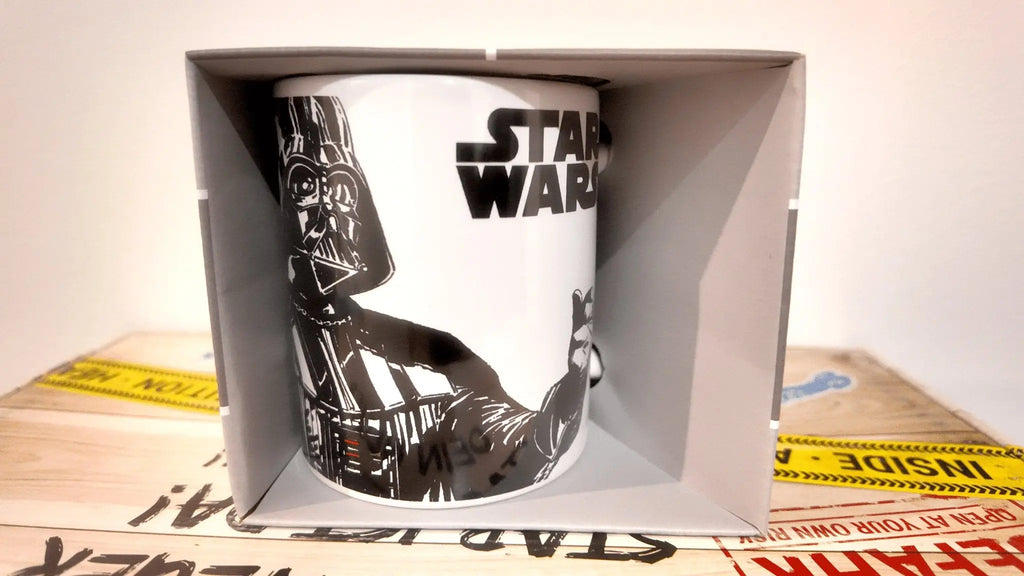 Weiße keramik-tasse mit schwarz-weiß darth vader illustration und star wars logo für kaffeegenuss