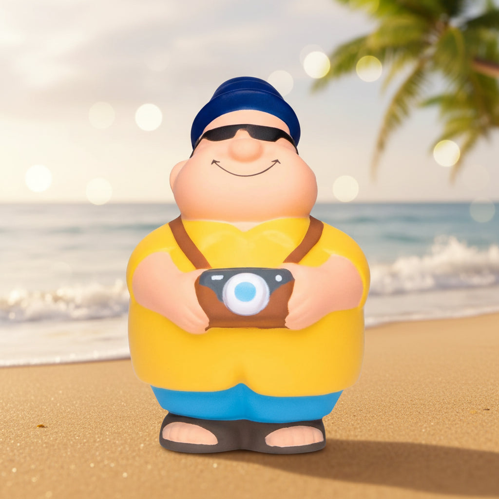 Gelbe und blaue anti-stress-quetsch-figur touri bert mit kamera trägt mütze sonnenbrille und sandalen