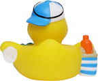Gelbe badeente mit blau weißer baseballkappe hält eine orange flasche im gestreiften strandtaschen-geschenkseturlaub