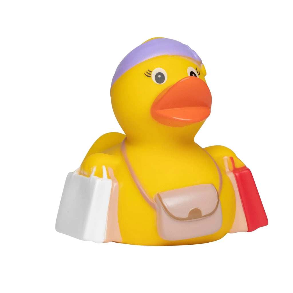 Gelbe badeente mit lila stirnband tragt einkaufstaschen und beigen umhängebeutel im urlaub geschenkset
