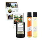 Ein geschenkset mit zwei glasflaschen aromatisierter öle in orange und hellgelb für wassermelonen feta salat