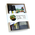 Präsentkorb mit zwei schwarzkappigen glasflaschen für öl und essig, kräuterbeutel und rezeptkarten für wassermelonen feta salat