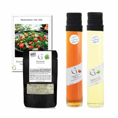 Zwei schlanke glasflaschen mit schwarzem verschluss eine mit bernsteinfarbenem haselnussbalsam und die andere mit blassem basilikumöl im wassermelonen feta salat-set geschenkkorb