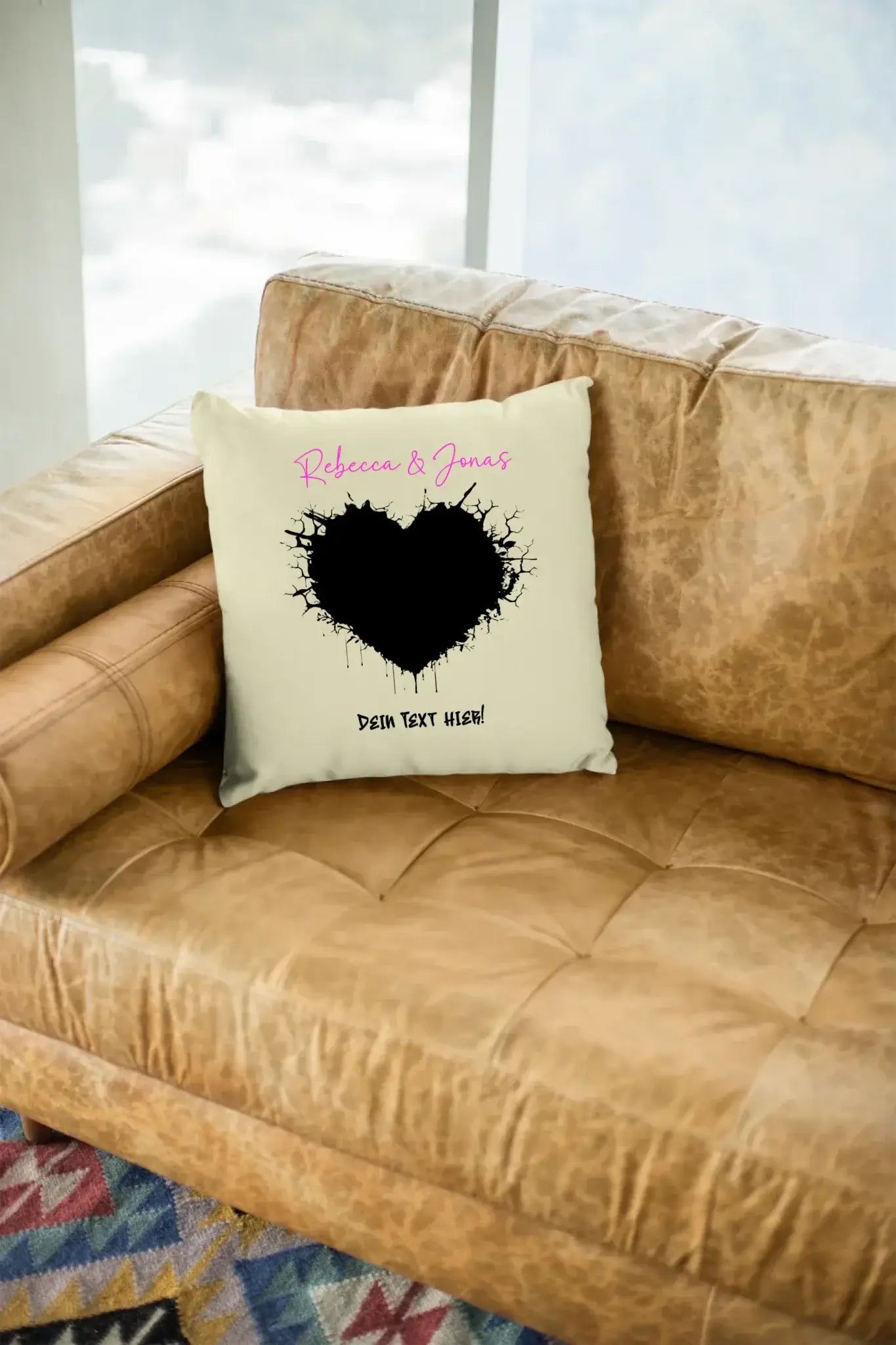 Cremefarbener kuschelkissen mit schwarzem gesprenktem herz und pinkem text rebecca & jonas aus der statement-collection